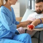 Female nurse preparing male donor for blood transfusion in hospital