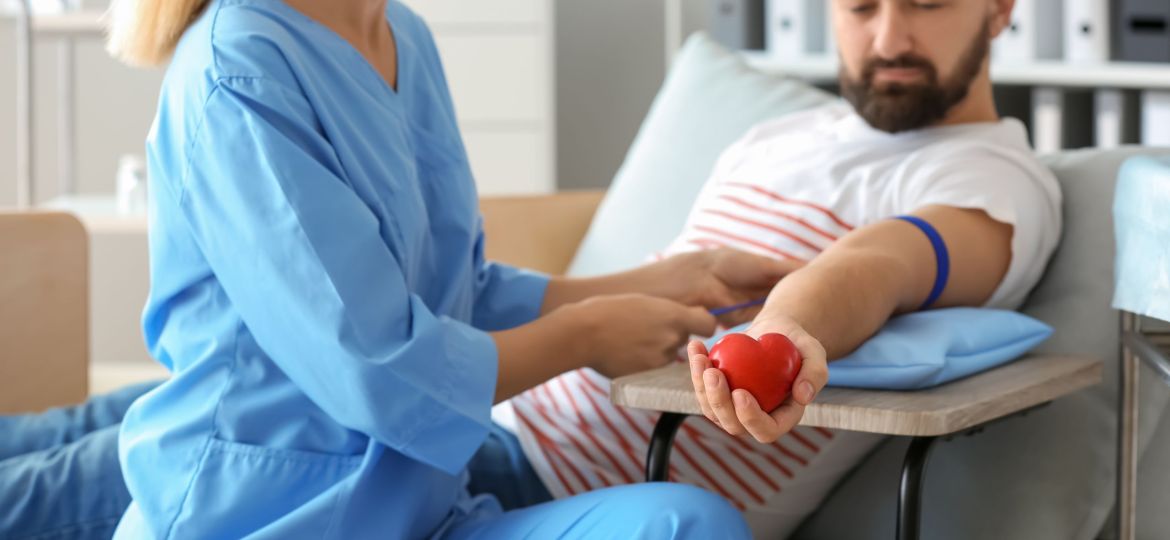 Female nurse preparing male donor for blood transfusion in hospital