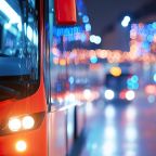 Public transit bus moving through city at dusk with Christmas illuminations.